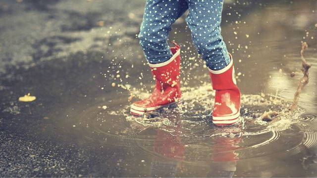 Child in red wellies jumping in a puddle